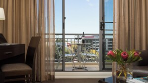 Una camera d'hotel con una scrivania, una sedia e vista su un balcone con posti a sedere all'aperto e un parapetto.