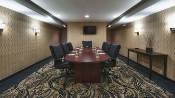 A conference room with a large table, chairs, and a patterned carpet.