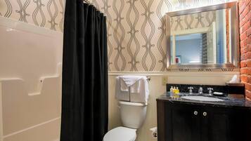 A bathroom with a white toilet, black shower curtain, and a black sink with a mirror above it.