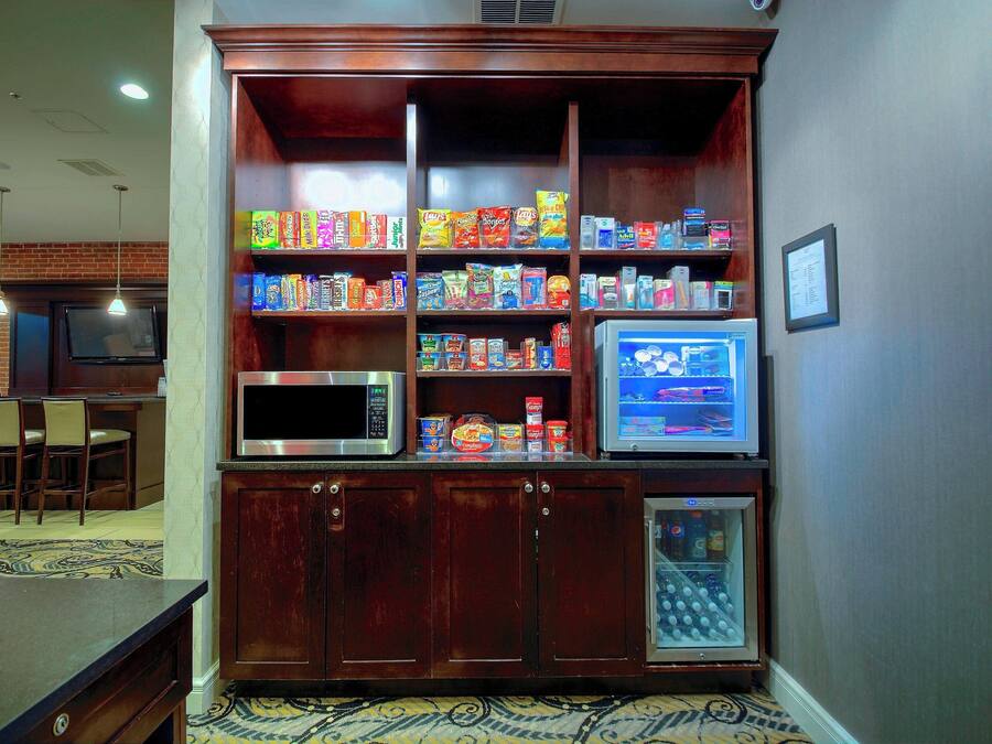 Eine Küchenzeile mit Mikrowelle, Kühlschrank und Vorratsschrank, gefüllt mit Snacks.