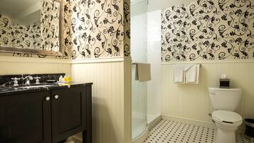 A bathroom with a black vanity, a glass shower enclosure, and a toilet.