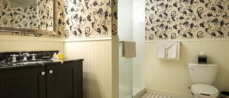A bathroom with a black vanity, a glass shower enclosure, and a toilet.