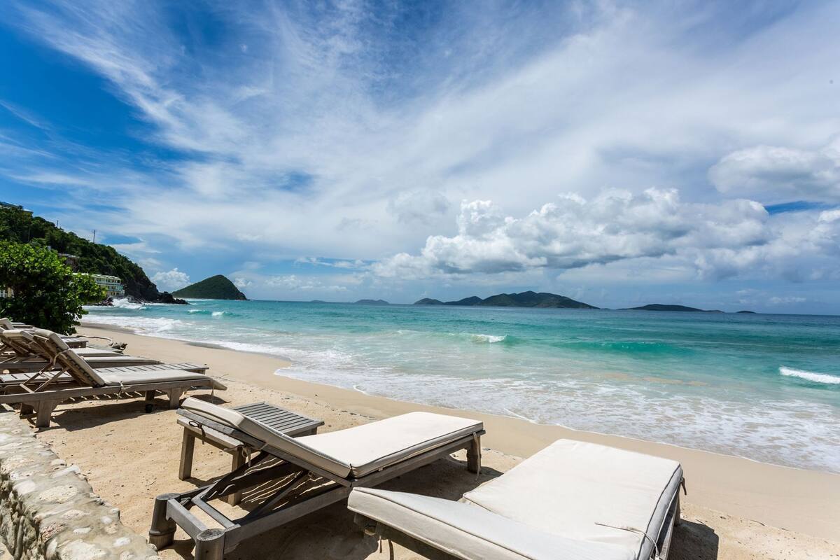 Une plage avec des chaises longues et une vue sur l’océan.