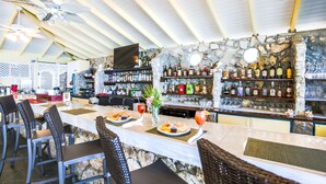 Een bar met een stenen muur, een houten plafond en barstoelen.