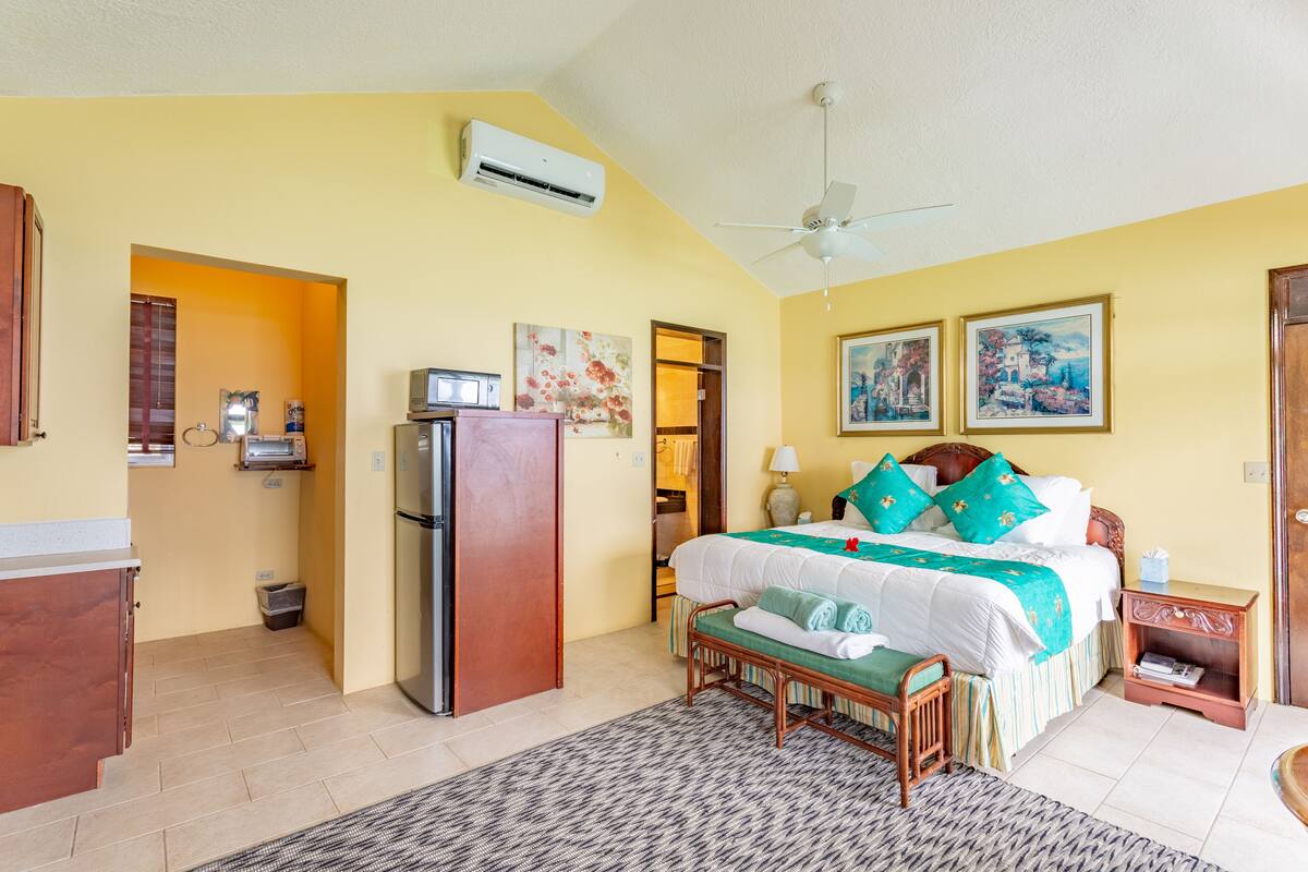 Quarto com cama, mesa de cabeceira e um pequeno espaço para sentar.