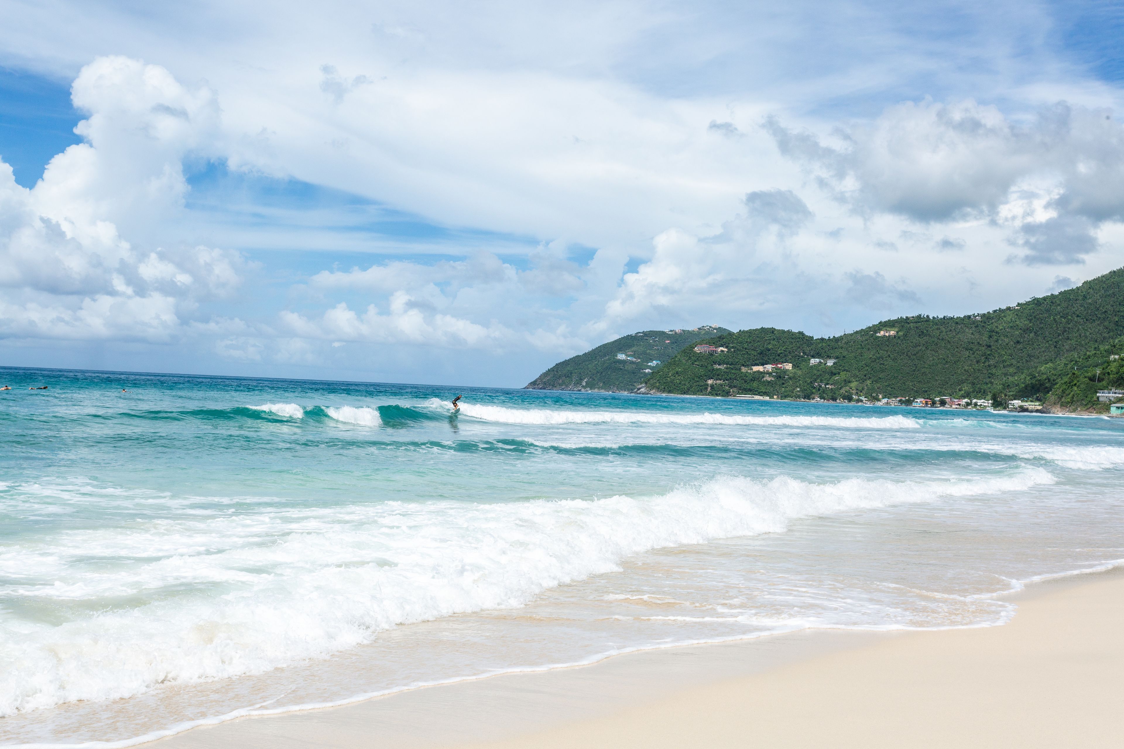 Une plage avec des vagues, un ciel dégagé et une montagne en arrière-plan.