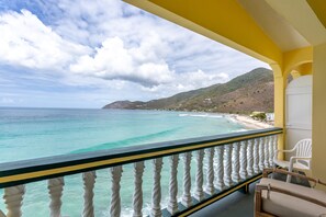 Enjoy the ocean view from this balcony with a bathtub, two beds, and comfortable seating for three.