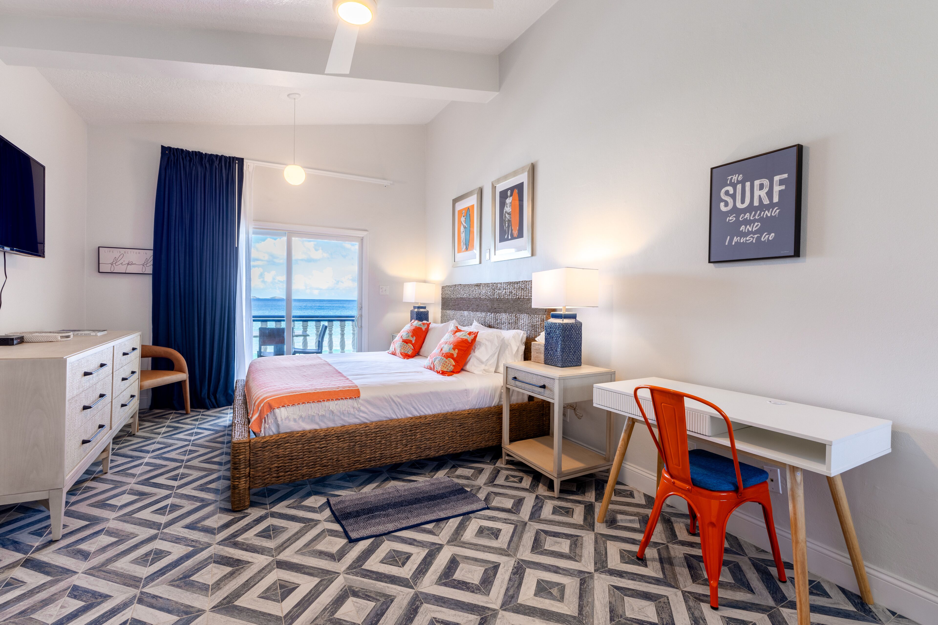 Een hotelkamer met een bed, bureau, stoel en een groot raam met uitzicht.