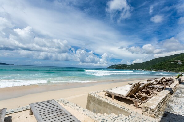 A beach with lounge chairs and a view of the ocean.
