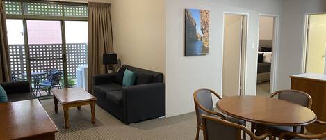 A room with a sofa, a dining table with chairs, a lamp, and a picture on the wall.