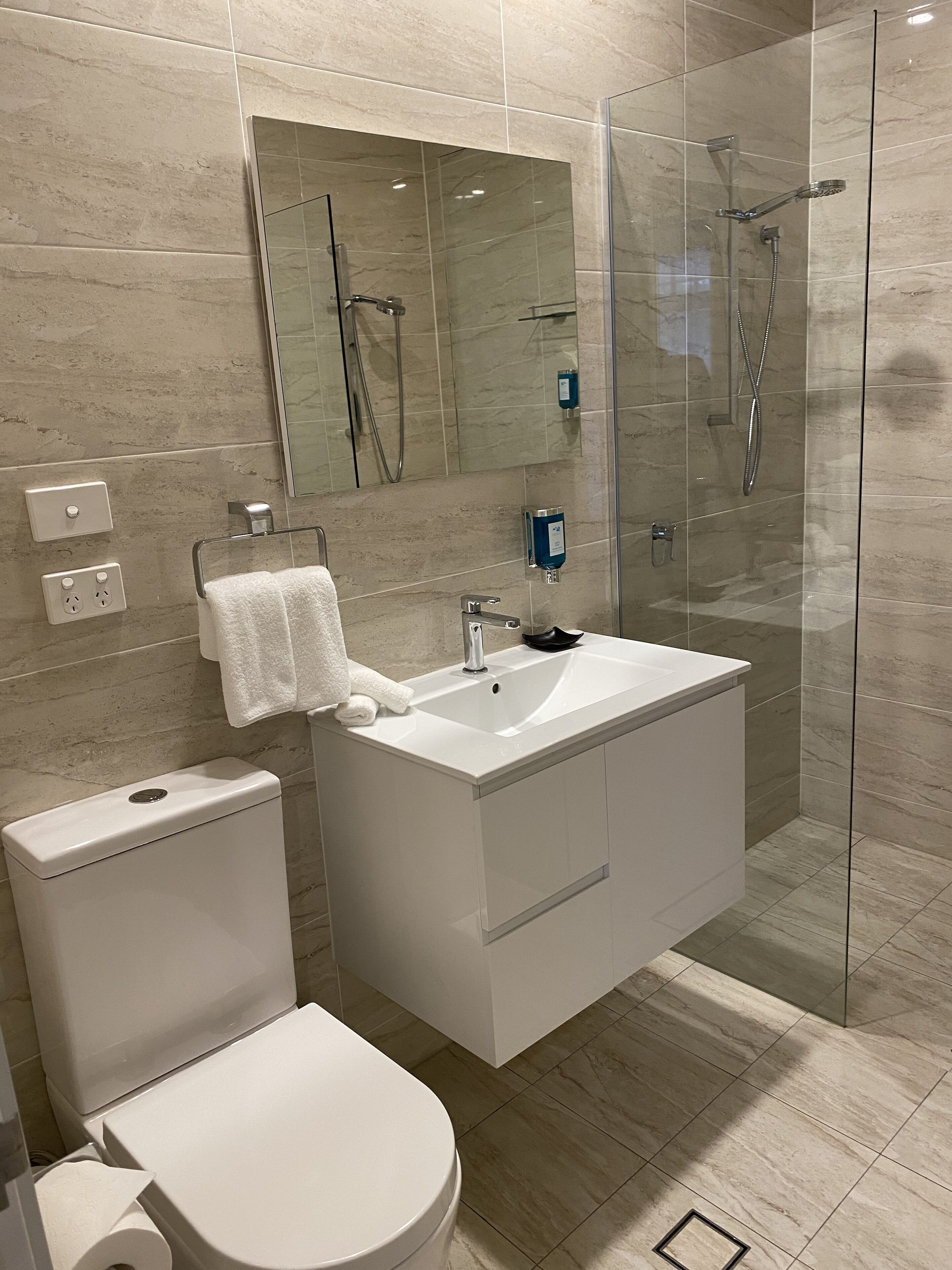 A modern bathroom with a glass-enclosed shower, a white sink, and a toilet.