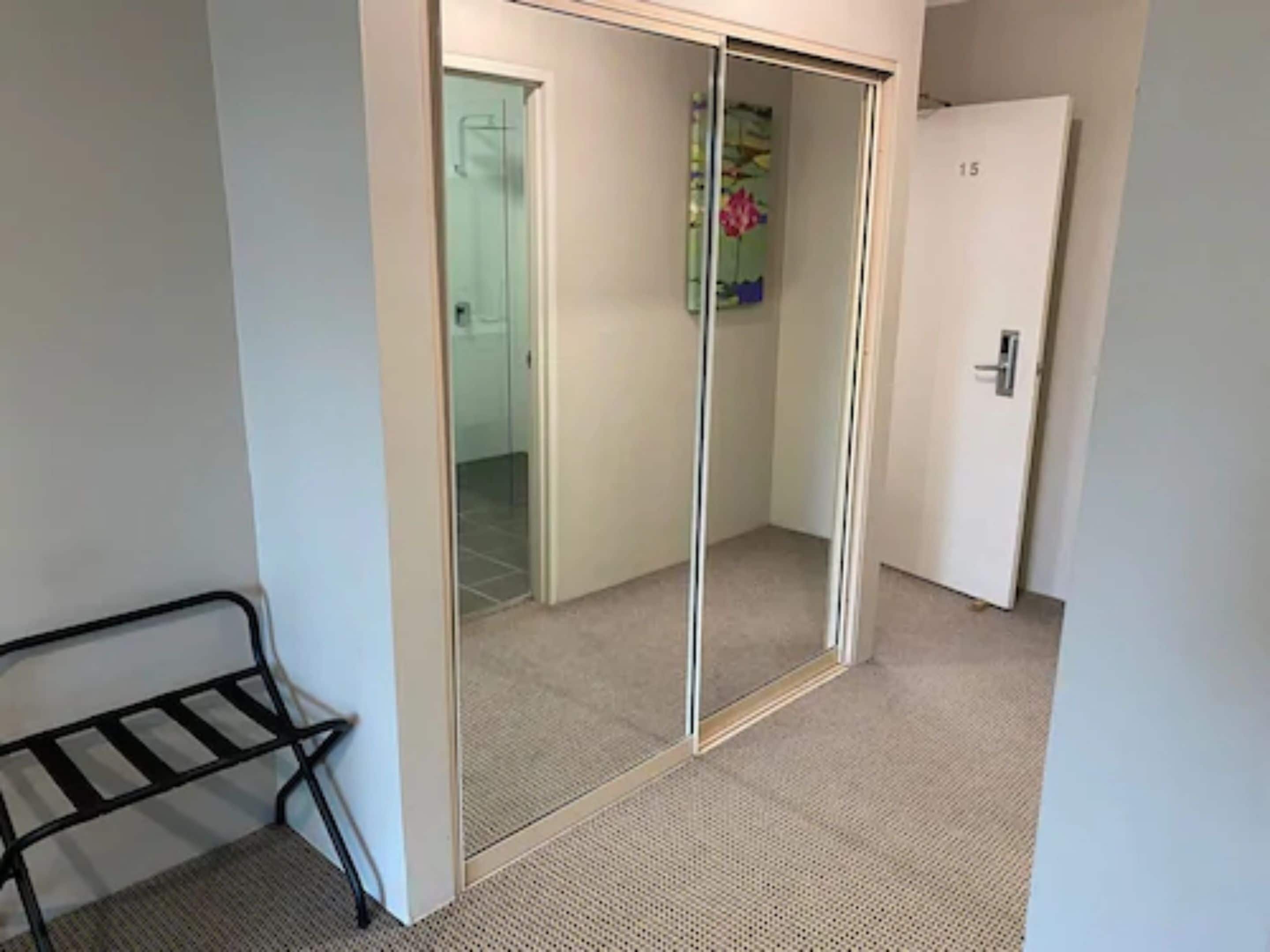 A room with a sliding door closet, a bench, and a door with a number.