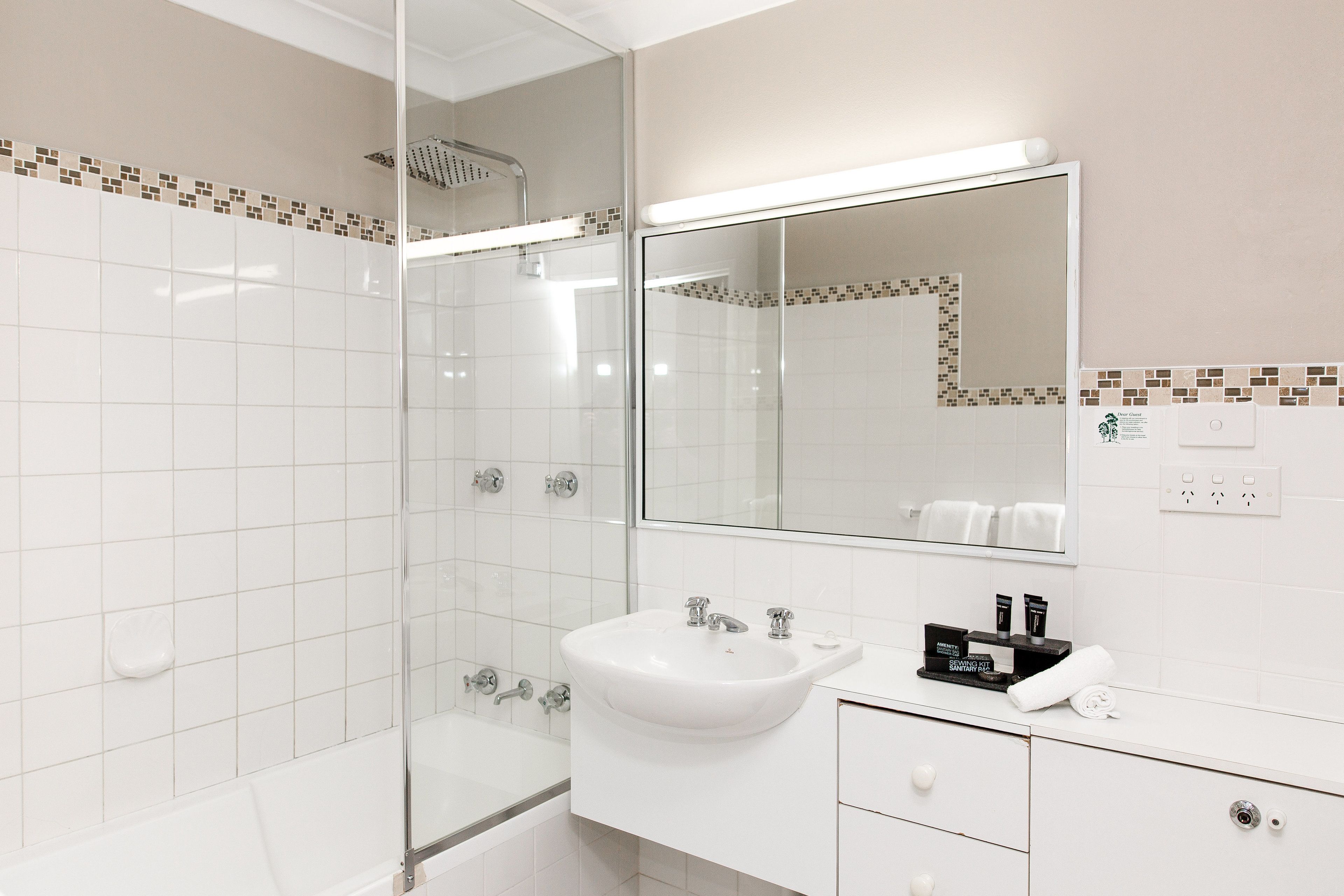 A modern bathroom with a glass-enclosed shower, a white sink, and a large mirror.