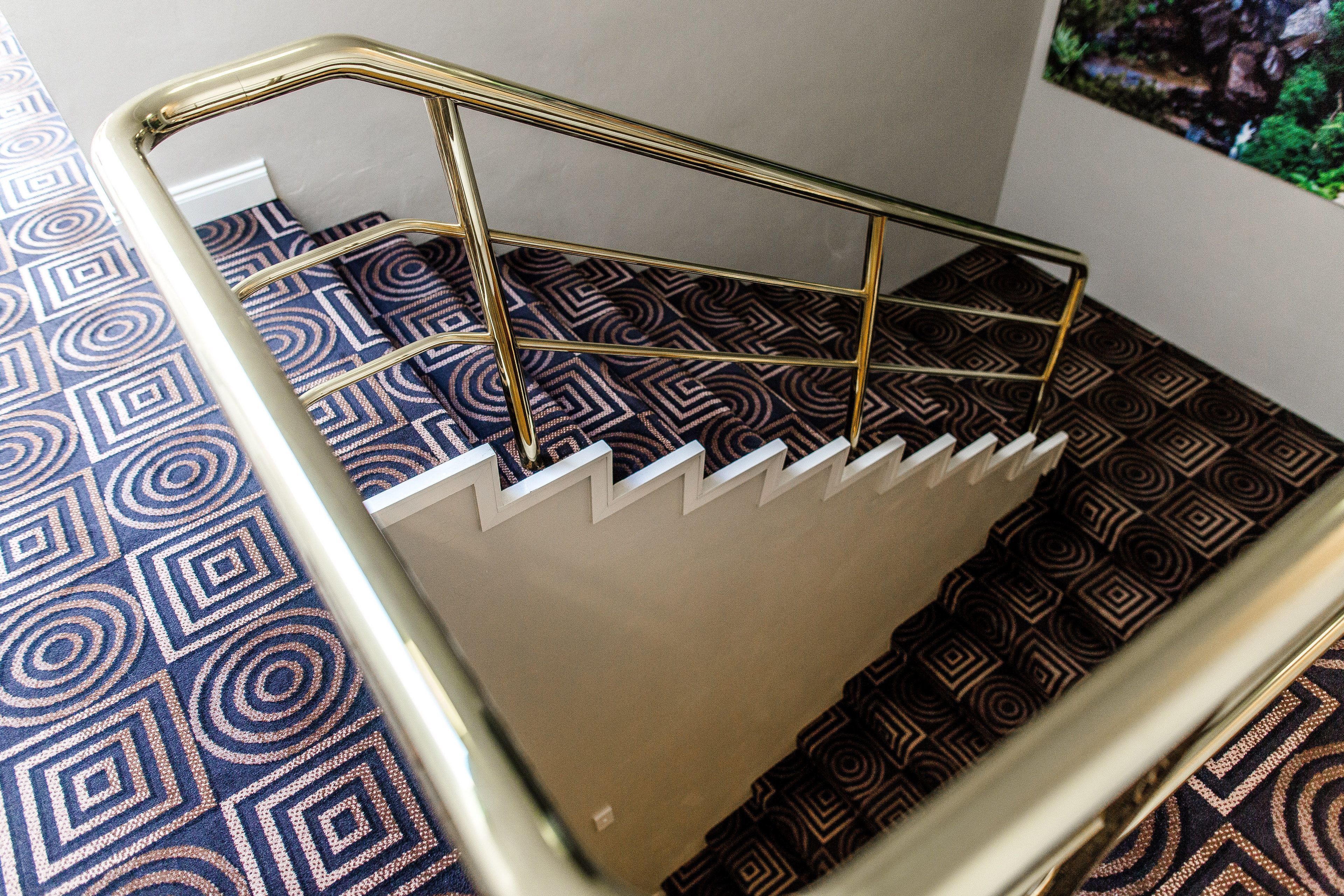 A staircase with a patterned carpet and a metal handrail.