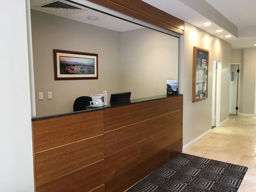 A reception desk with a wooden panel design, a framed picture on the wall, and a patterned rug on the floor.