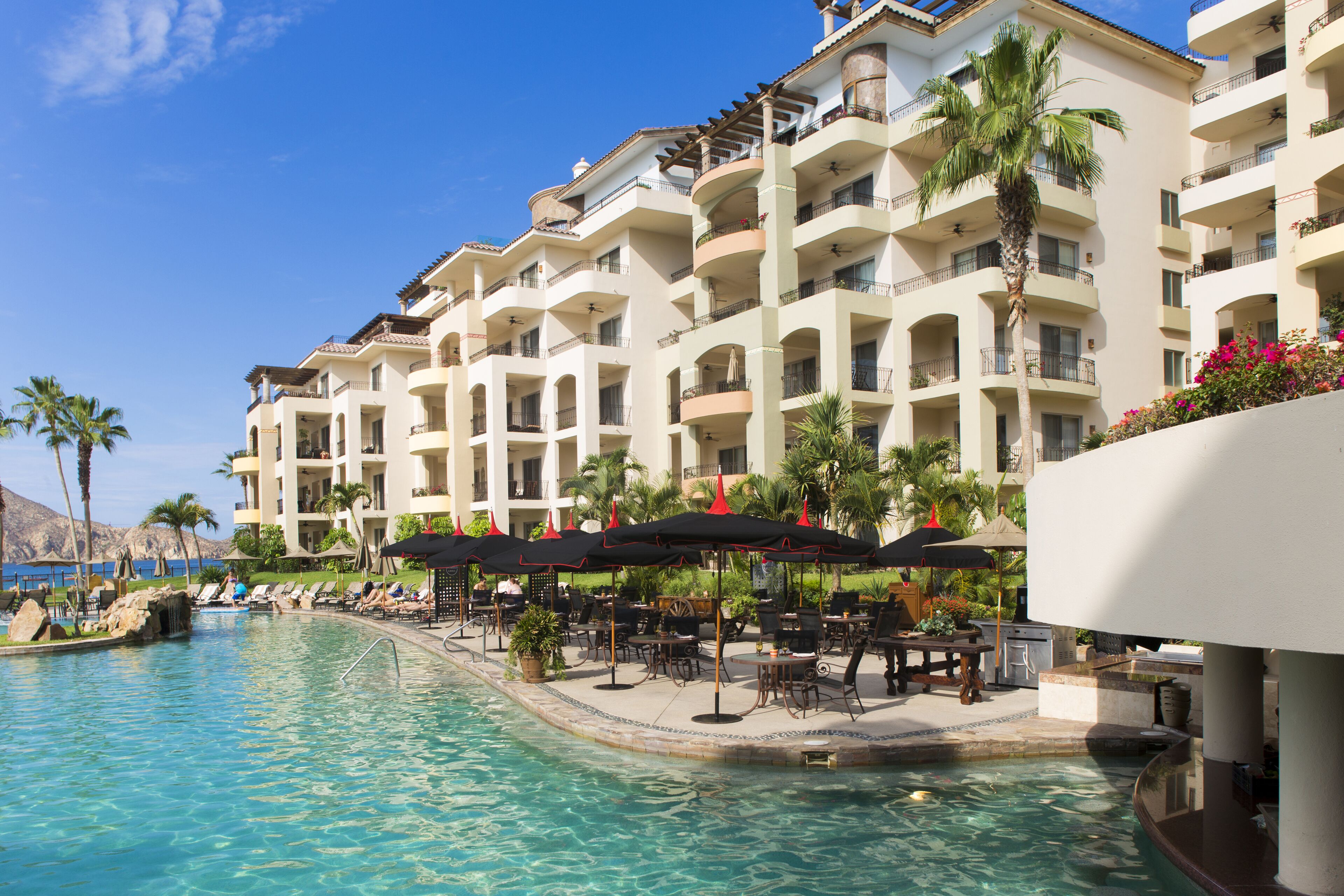 Un hotel con piscina, mobiliario exterior y balcones.