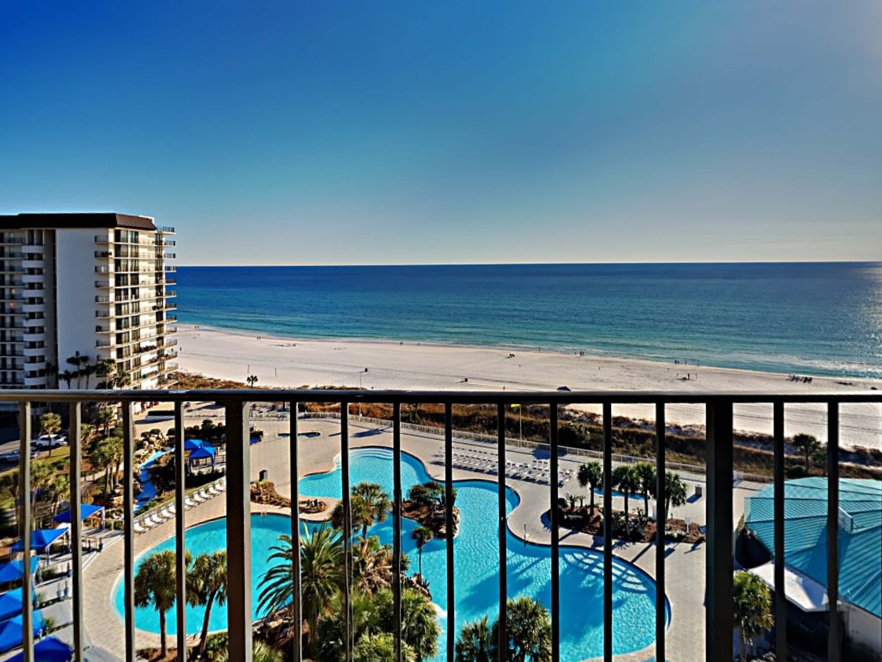 A resort with a beach view, a pool area, and a high-rise building.