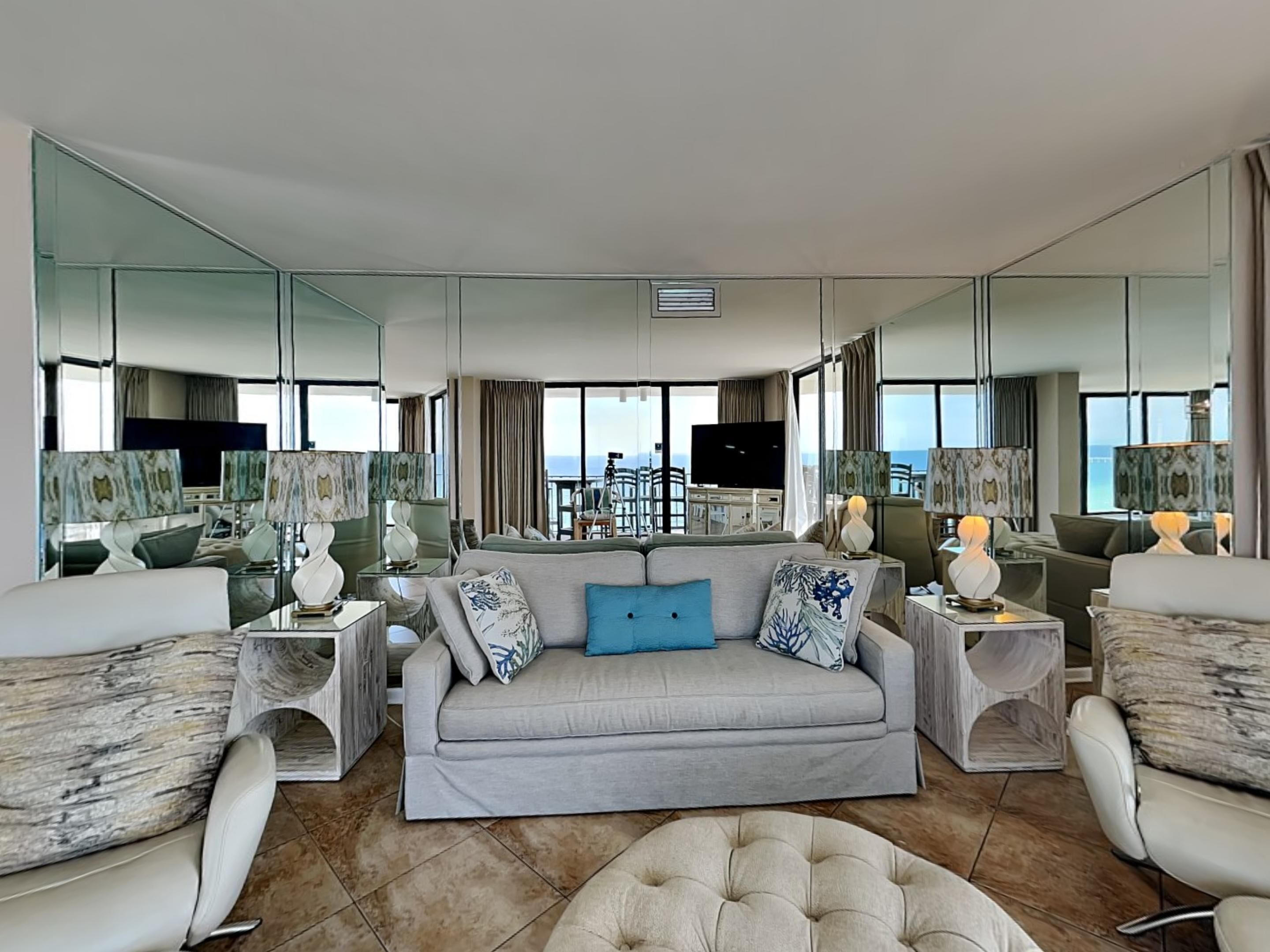 Ein modernes Hotelzimmer mit einer großen Couch, zwei Sesseln, einem Couchtisch und einem Fernseher. Das Zimmer verfügt über große Fenster mit Blick auf die Stadt.