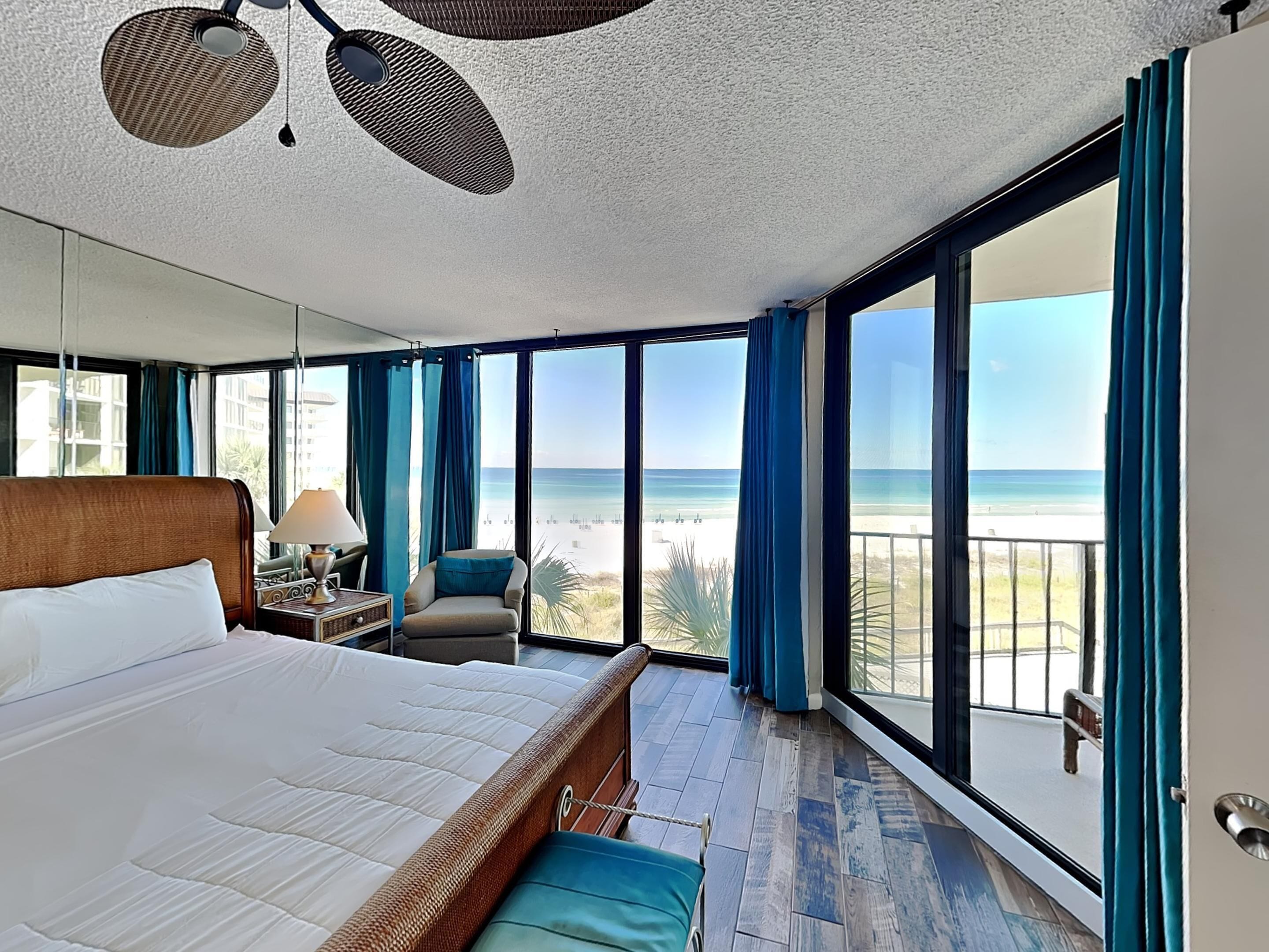 Une chambre d’hôtel avec un grand lit, une chaise, une table de chevet et une vue sur la plage.