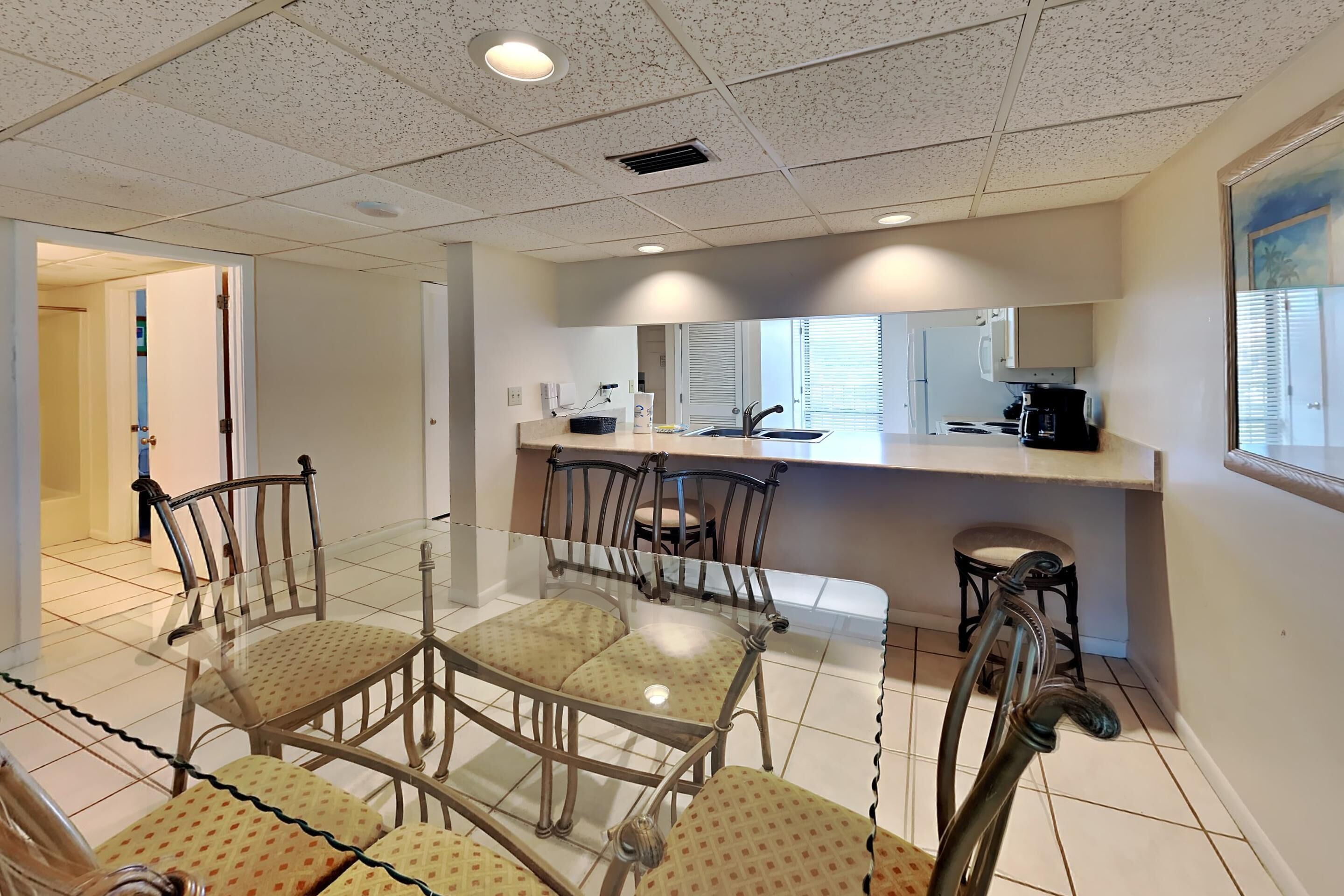 Una cocina moderna con una mesa de vidrio, sillas y un lavamanos integrado.