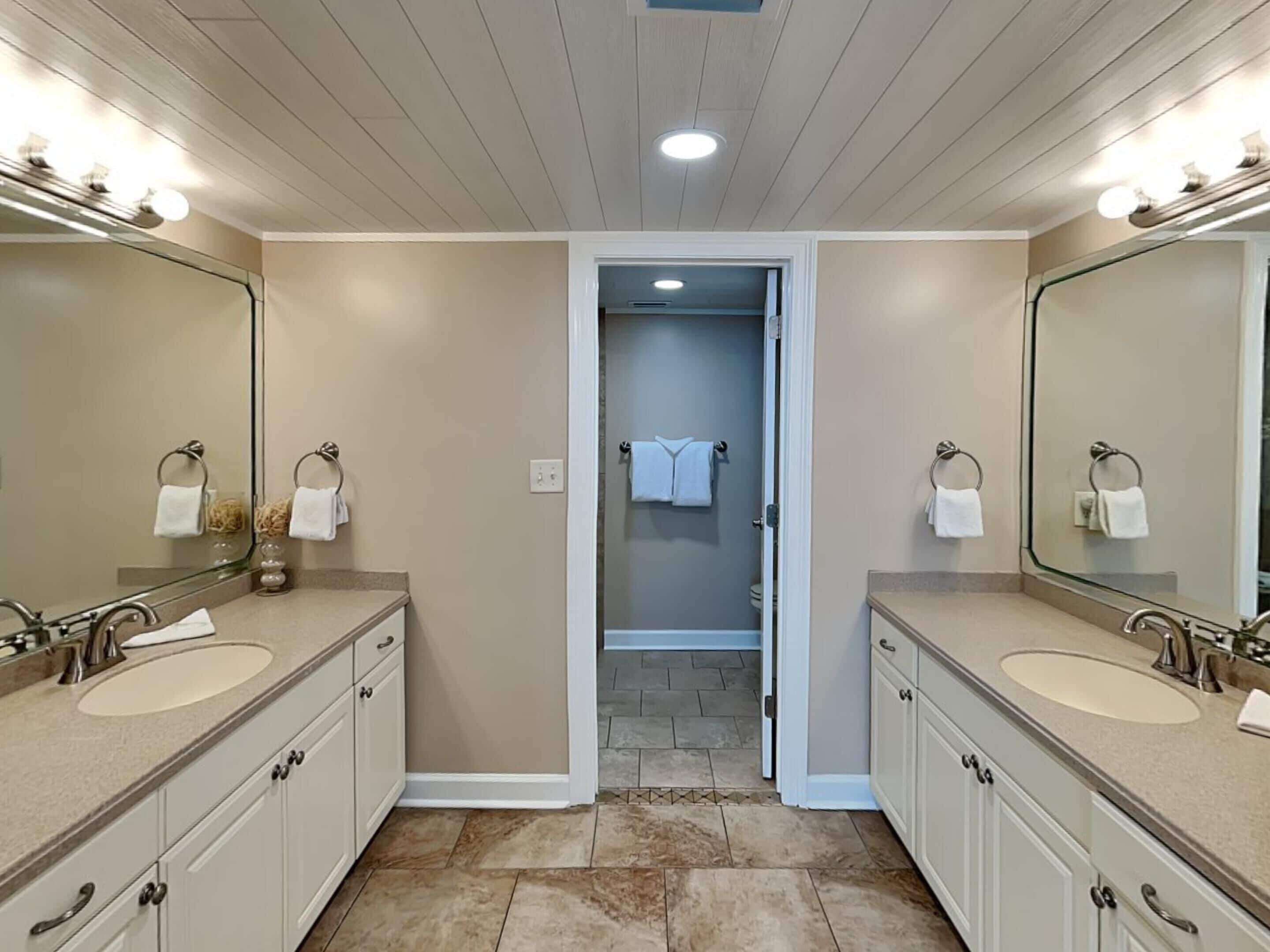 A modern bathroom with two sinks, large mirrors, and a walk-in shower.