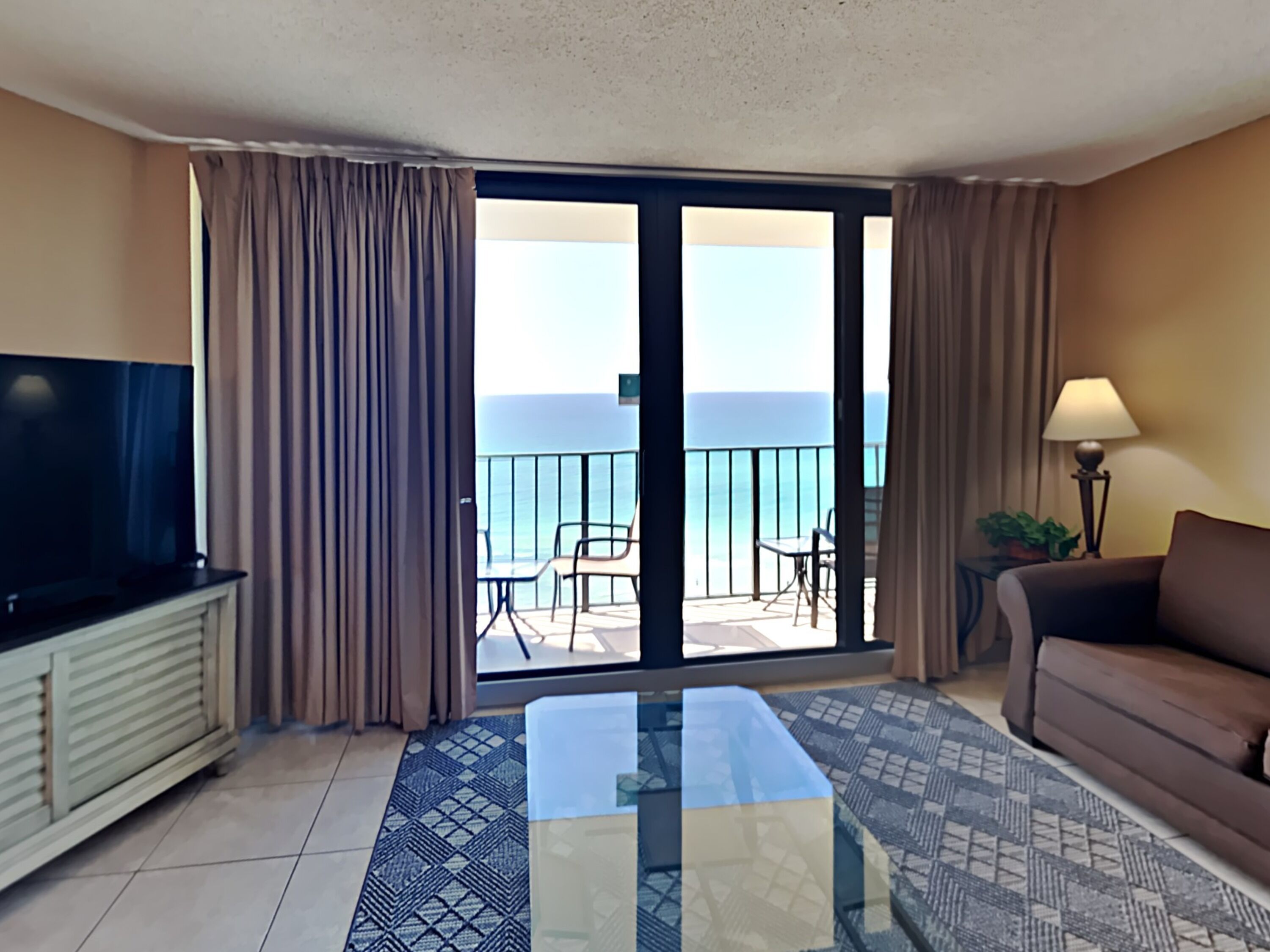Ein Hotelzimmer mit Balkon, Fernseher, Sofa und Tisch.