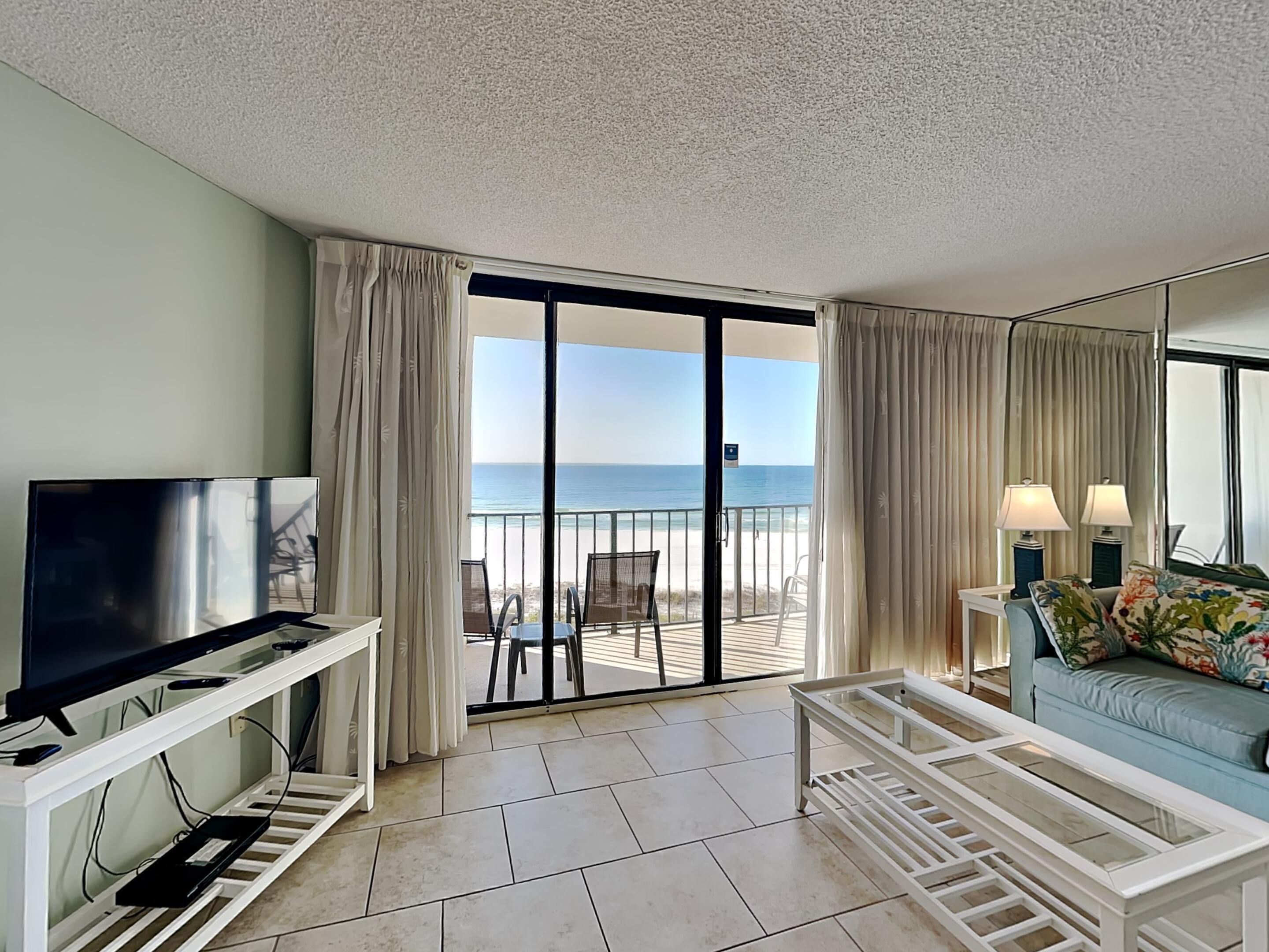 Una habitación de hotel con balcón, televisión, sofá y mesa de centro.