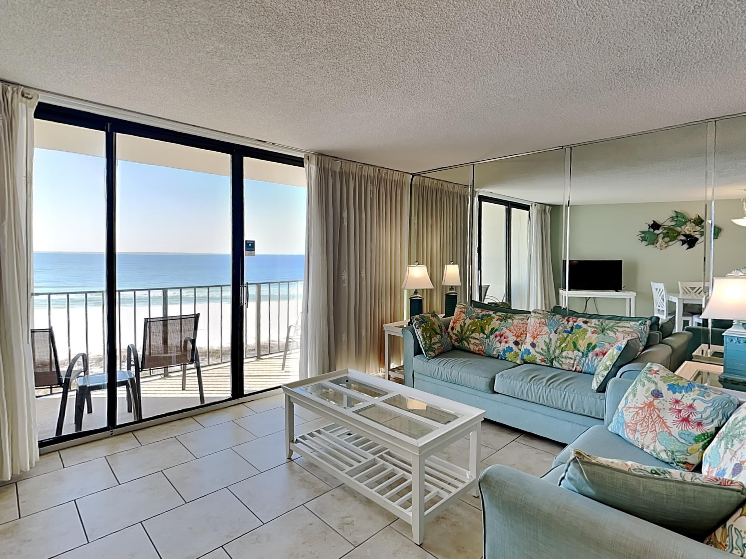 Een ruime woonkamer met een grote schuifpui die uitkomt op een balkon met uitzicht op de oceaan.