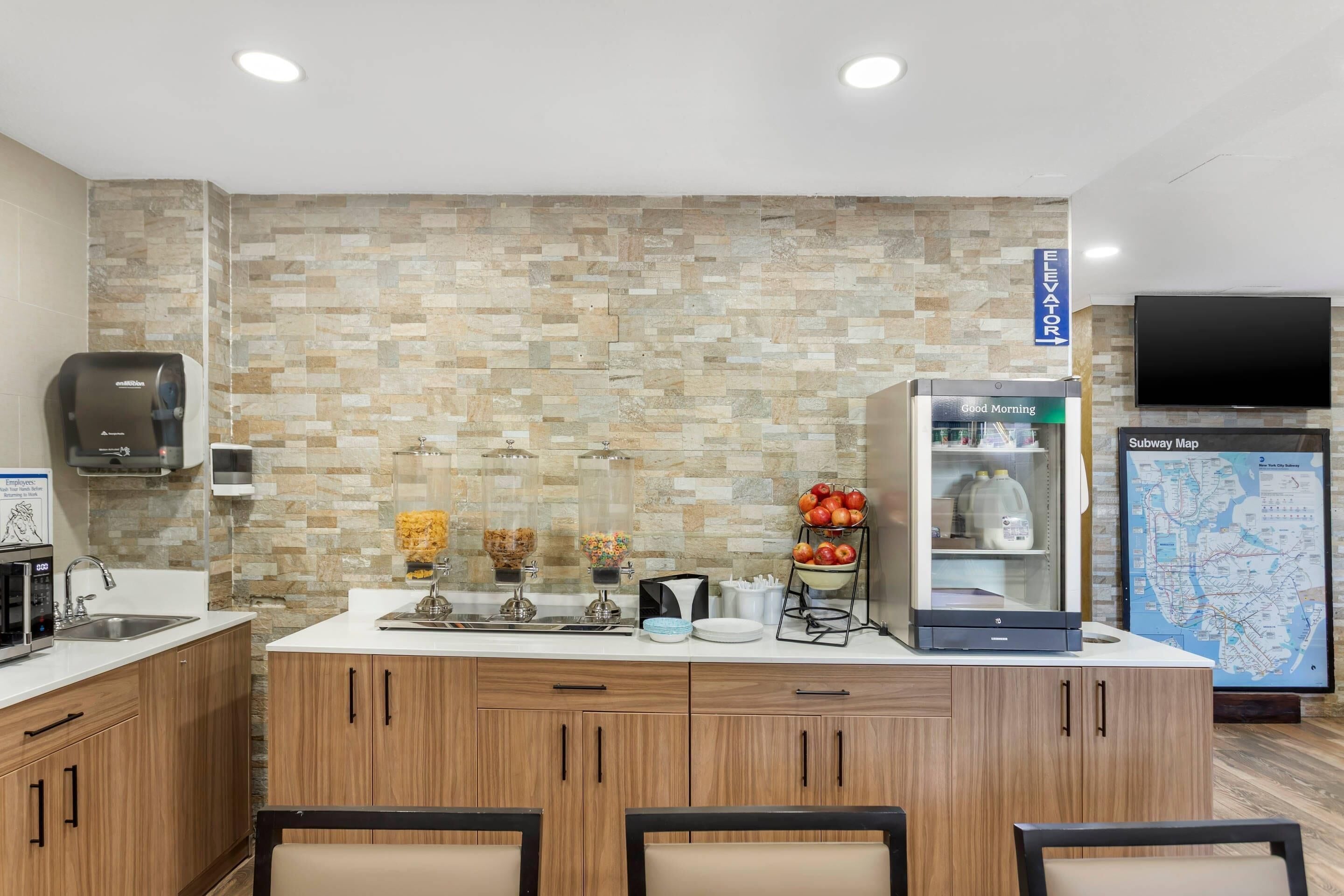 Una cocina moderna con protector contra salpicaduras de piedra, un refrigerador, una cafetera y un mapa del metro de Subway en la pared.