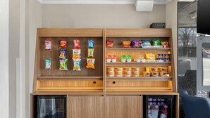 Una selección de aperitivos y chips, un refrigerador con bebidas y una máquina expendedora.