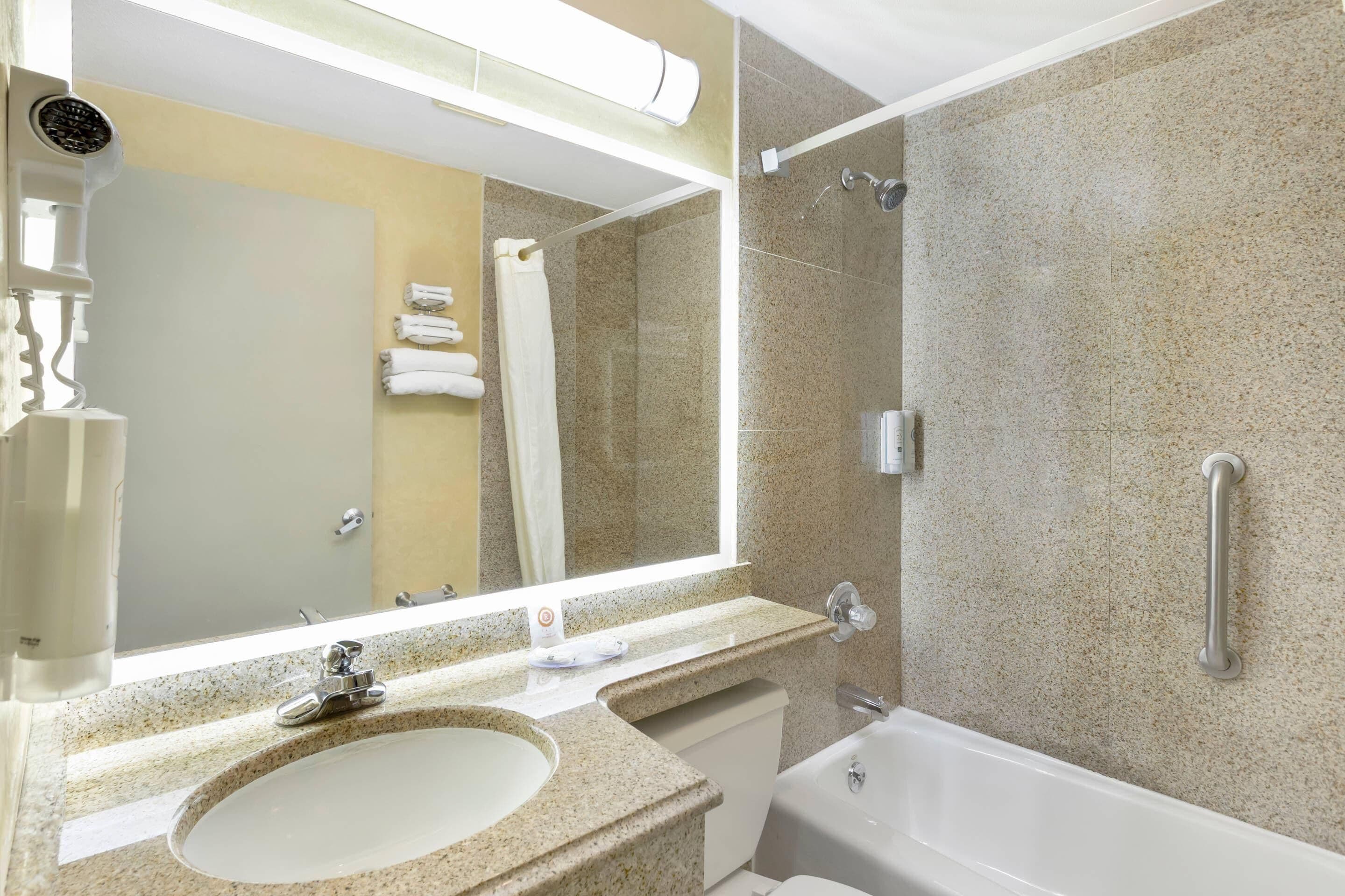 A bathroom with a sink, mirror, towel rack, shower, and bathtub.