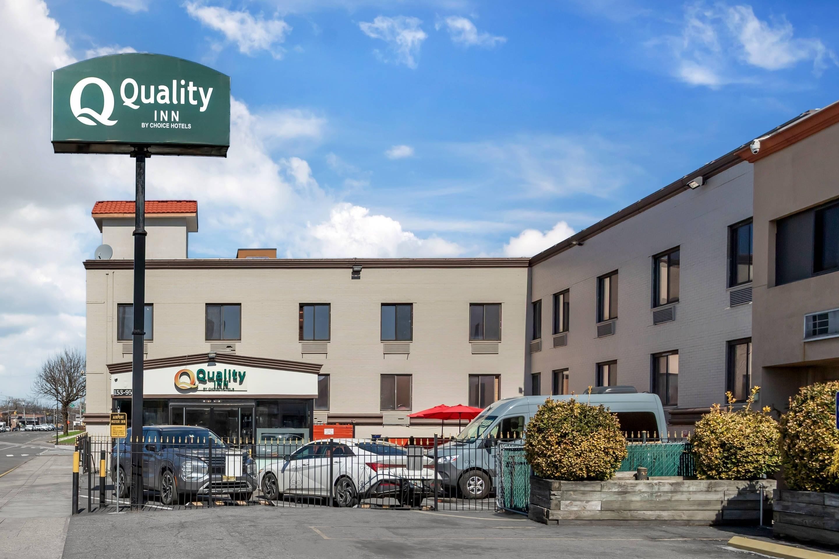 A Quality Inn by Choice Hotels building with a parking lot, a signboard, and a gated entrance.