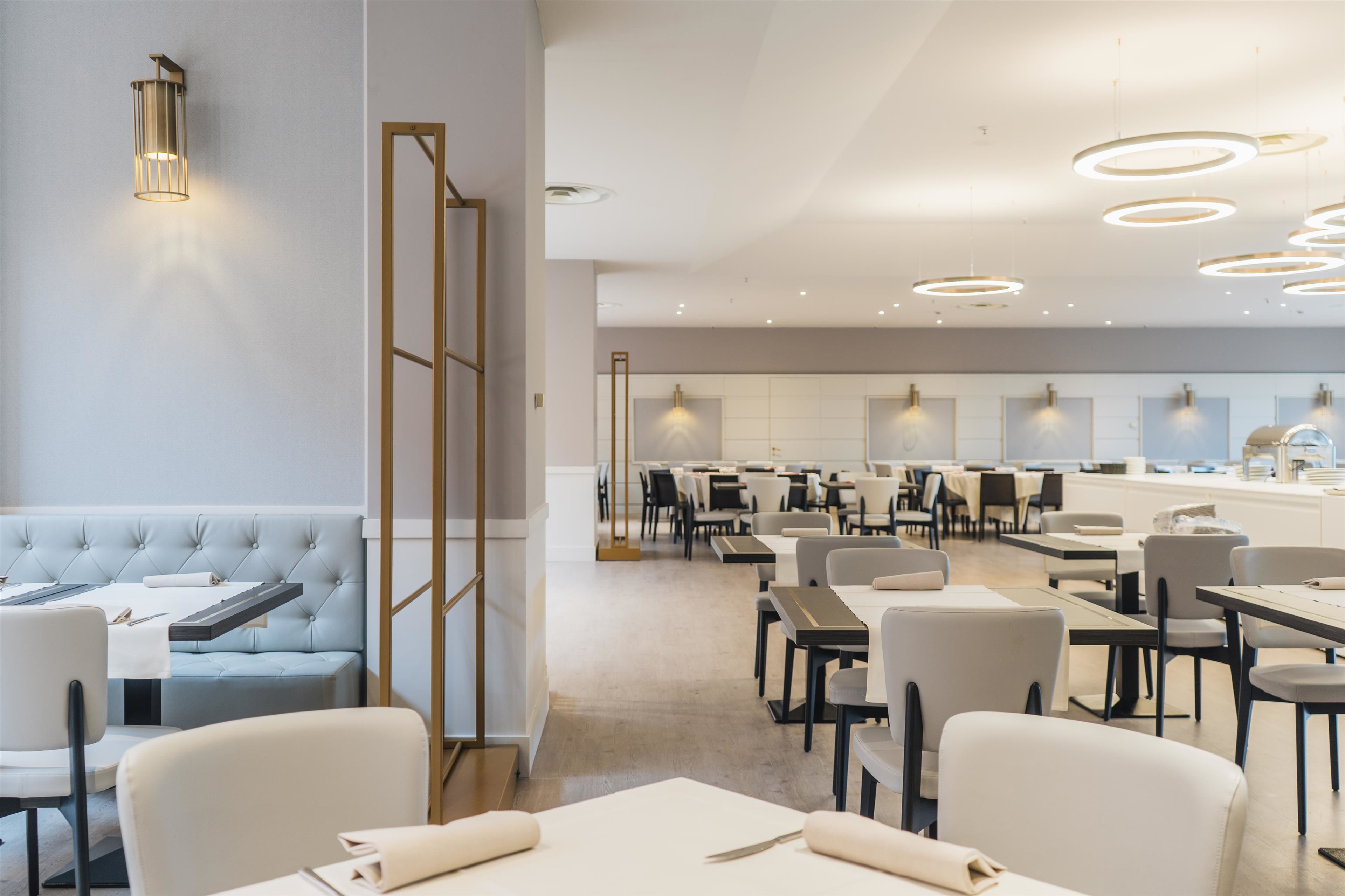 Un ristorante moderno con un lungo bancone, diversi tavoli e un'area salotto con una panca imbottita.