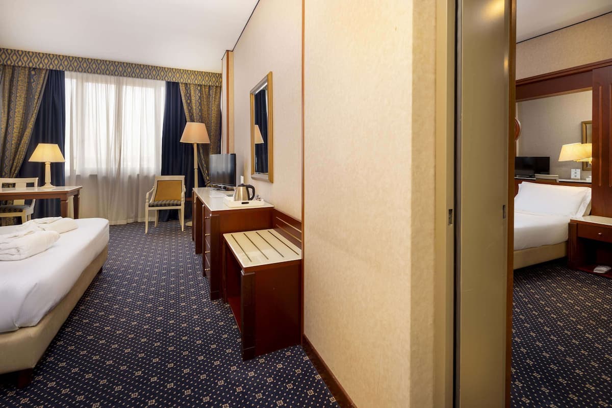 Ein Hotelzimmer mit Bett, Schreibtisch, Stuhl, Fernseher und Bad.
