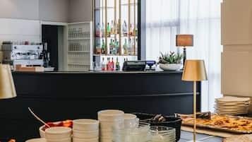 A breakfast buffet with pastries, drinks, and a bar area with a variety of bottles.