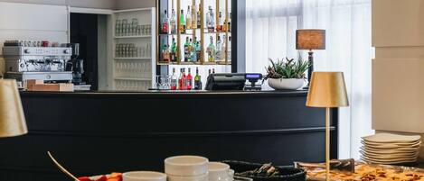 A breakfast buffet with pastries, drinks, and a bar area with a variety of bottles.
