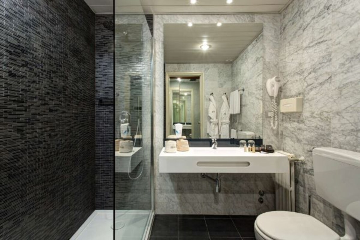 Une salle de bain moderne avec une douche à parois de verre, un lavabo blanc avec un meuble-vasque et des toilettes.