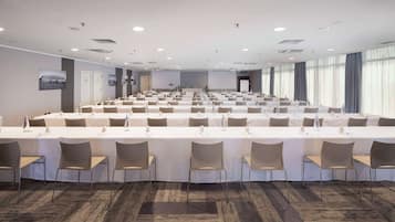 Une salle de conférence dotée de plusieurs tables et chaises, ainsi que de bouteilles d’eau et de plaques nominatives.