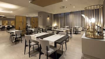 A modern dining area with multiple tables and chairs, arranged in a spacious layout.