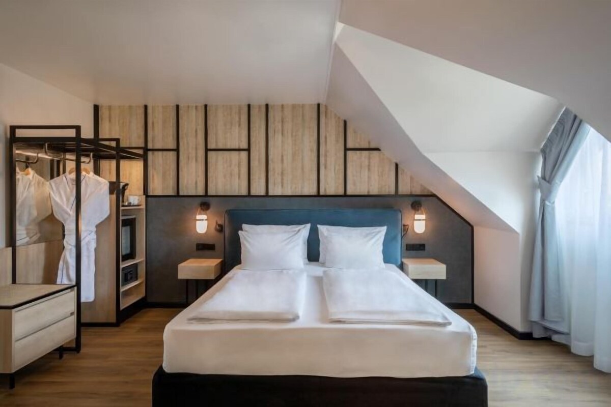 Una habitación de hotel moderna con una cama grande, un armario y un espejo.