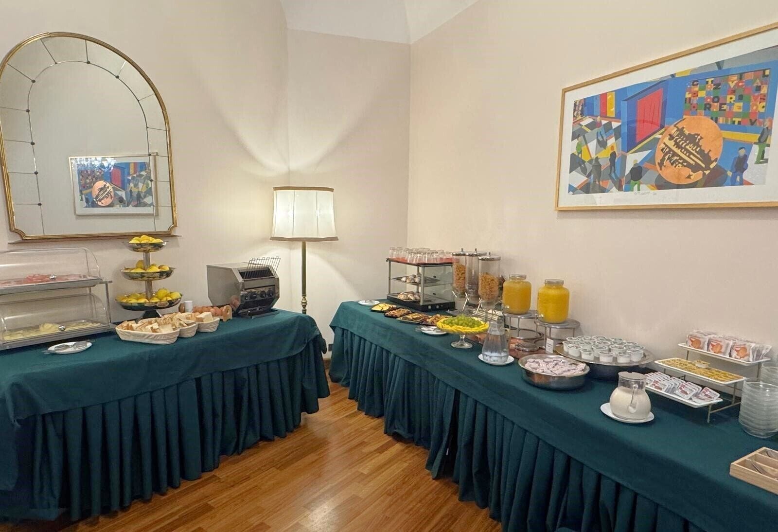 A buffet setup with various food items and beverages, a grill, and a framed artwork on the wall.