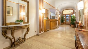 Un lobby de hotel con un espejo imponente, una consola decorativa y una mesa de recepción.