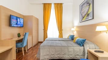 A hotel room with a bed, a desk, a chair, a TV, and a painting on the wall.