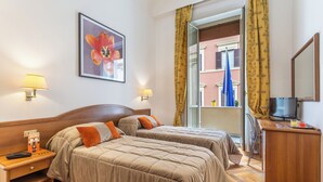 Habitación de hotel con dos camas, un escritorio con televisor y una ventana con cortinas.