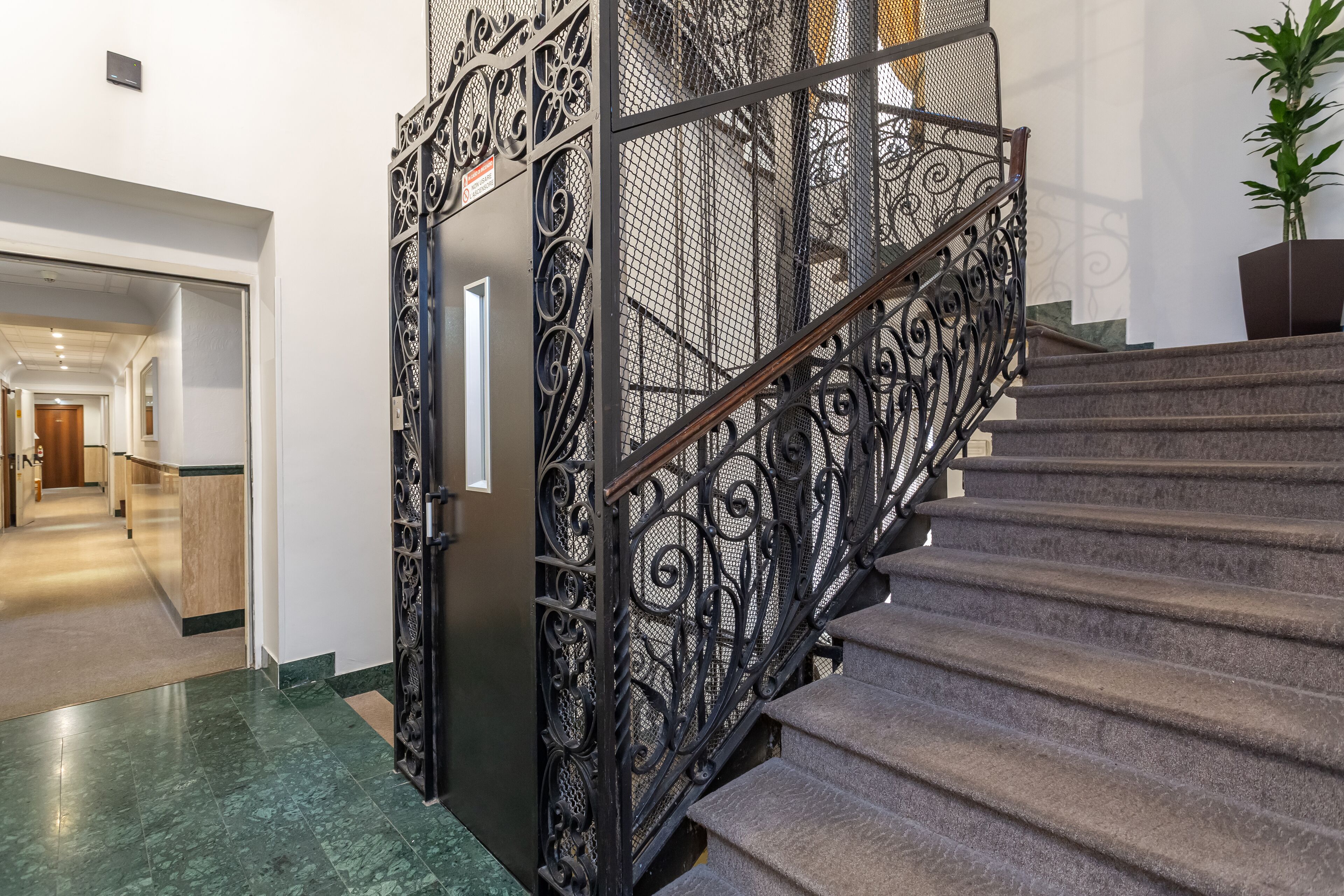 Un escalier orné de rampes en métal ouvragé, avec un pot de fleurs placé en haut.