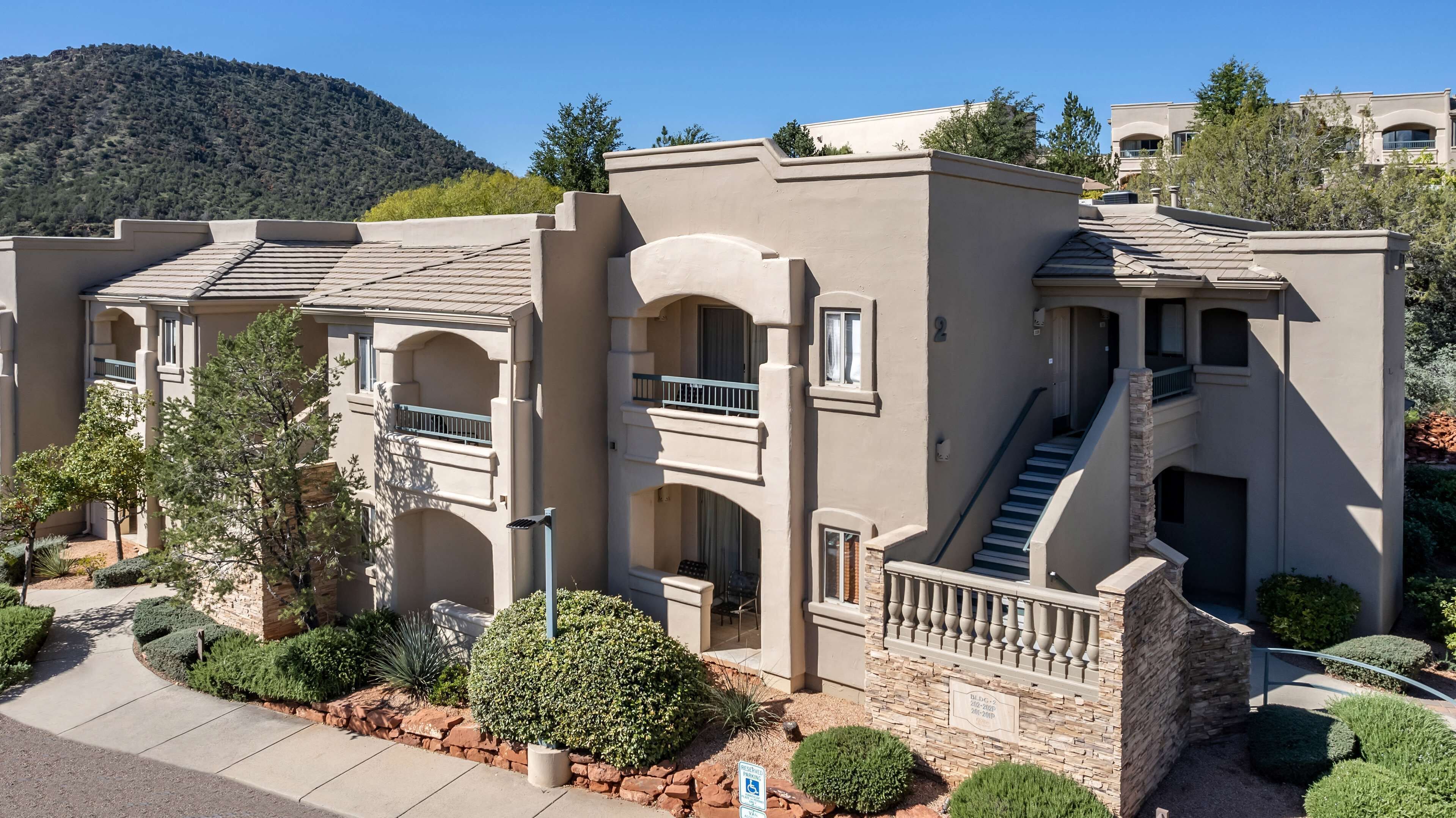 A multi-story residential building with balconies, a staircase, and a landscaped garden.