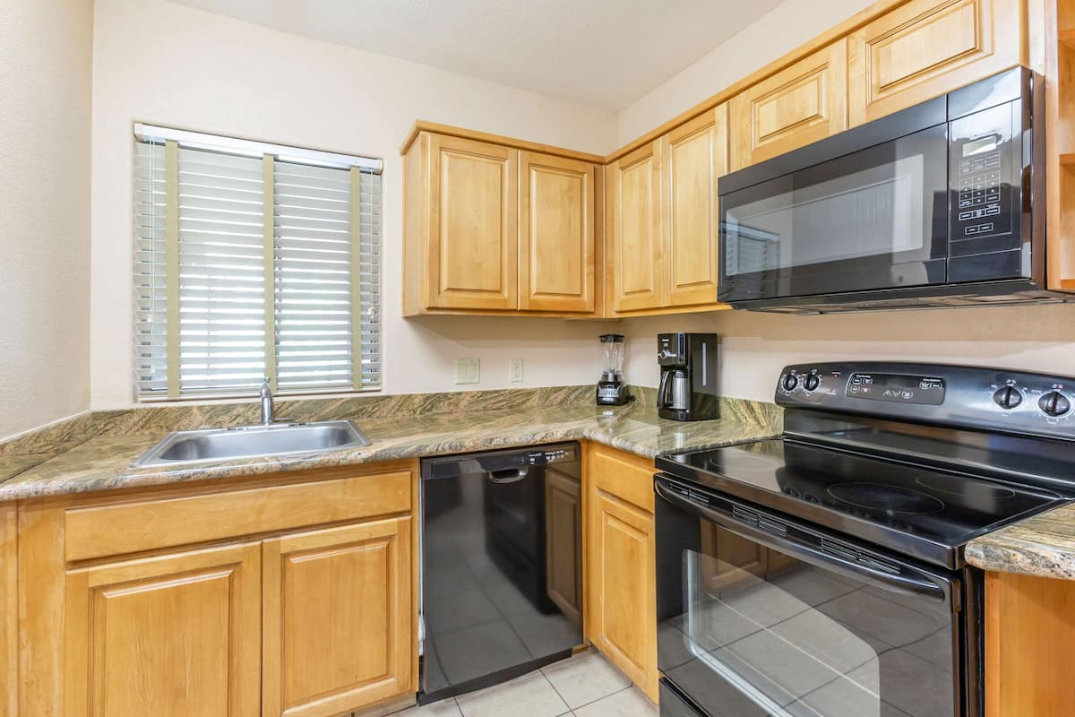 A kitchen with wooden cabinets, a built-in microwave, a dishwasher, and a stove.