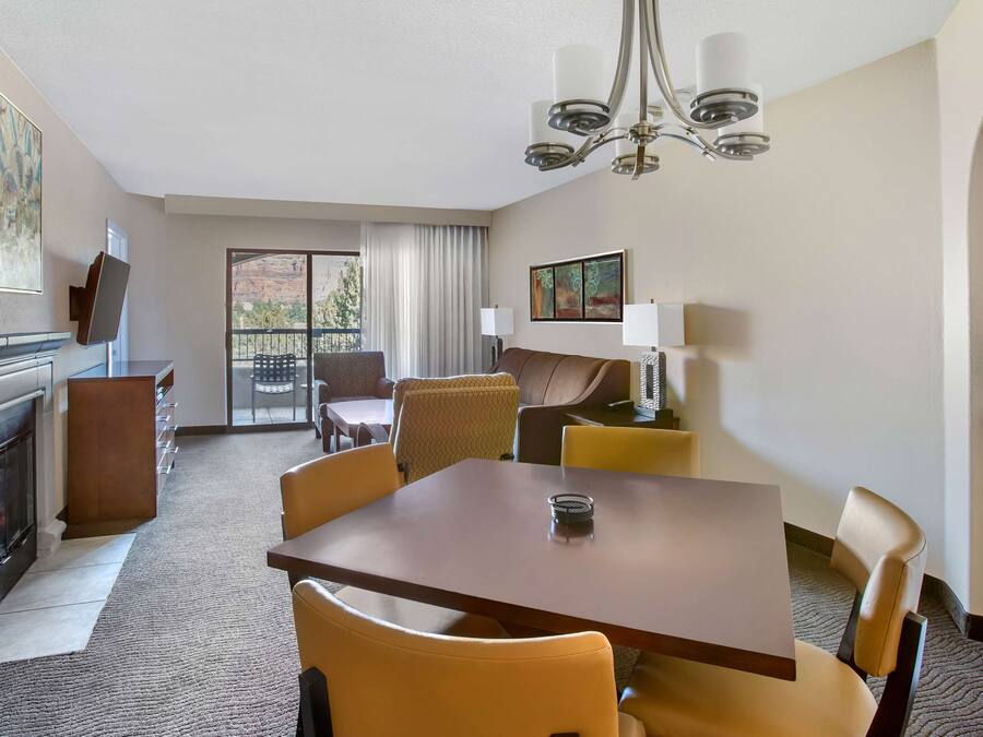 Une chambre d’hôtel dotée d’un coin repas, d’une cheminée, d’un balcon avec vue et d’un lustre.