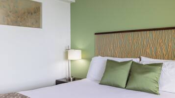 Una habitación de hotel con una cama, una mesita de noche, una lámpara y una obra de arte en la pared.