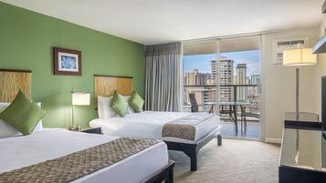 A hotel room with two beds, a balcony with a city view, a desk, and a chair.